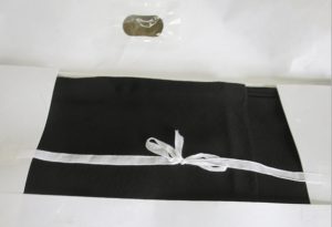 着物のお手入れに最適な、折りたたんだ黒い布を白いリボンで結び、小さな透明なプラスチックの窓が付いた白いパッケージに入れます。.